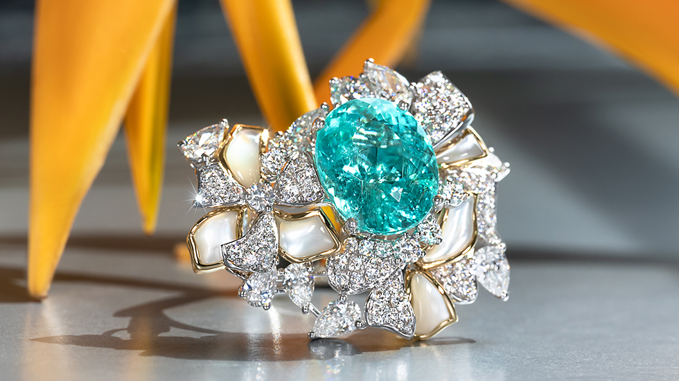Elegant Paraiba tourmaline gemstone ring with a light blue neon electric hue, adorned with super sparkly diamonds and an intricate mother of pearl inlay.