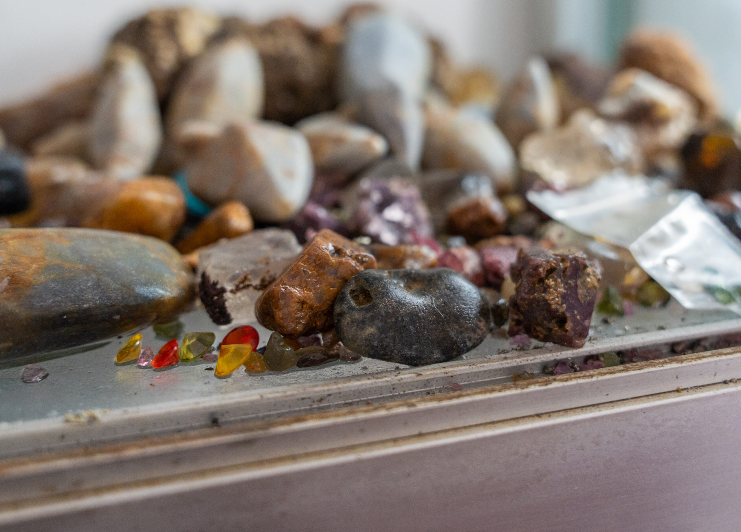 Assorted rough gemstones in various colours and shapes arranged on a surface.