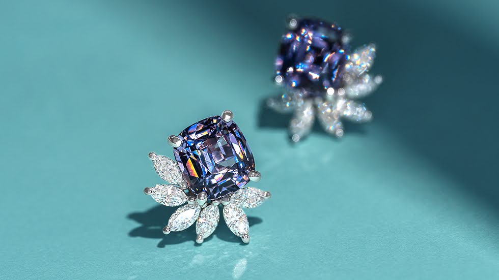 Cushion cut grey spinel earring studs adorned with a floral marquise diamond spray, set against a blue background.