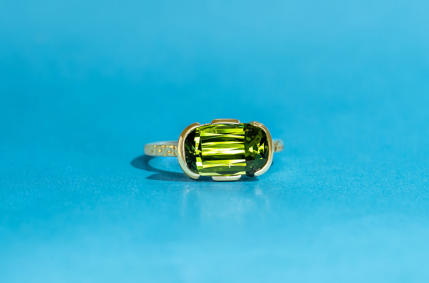 The warm tones of this oval-cushion cut Peridot are nicely complemented by the yellow gold of the ring it’s set in.